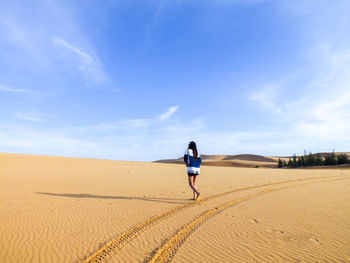 Rear view of women walking in desert against sky