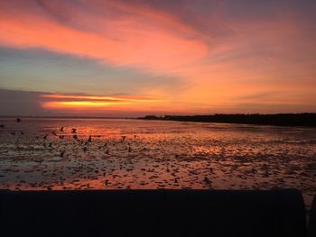 Scenic view of sea against dramatic sky during sunset