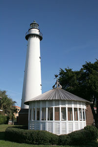 Lighthouse by building against clear sky