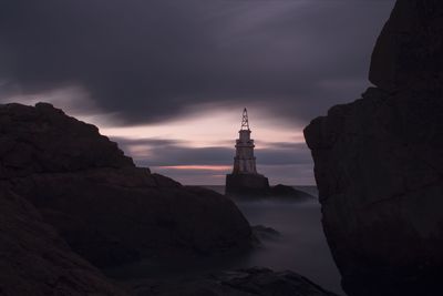 View of buildings and rocks against cloudy sky