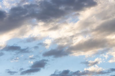 Low angle view of sunlight streaming through clouds