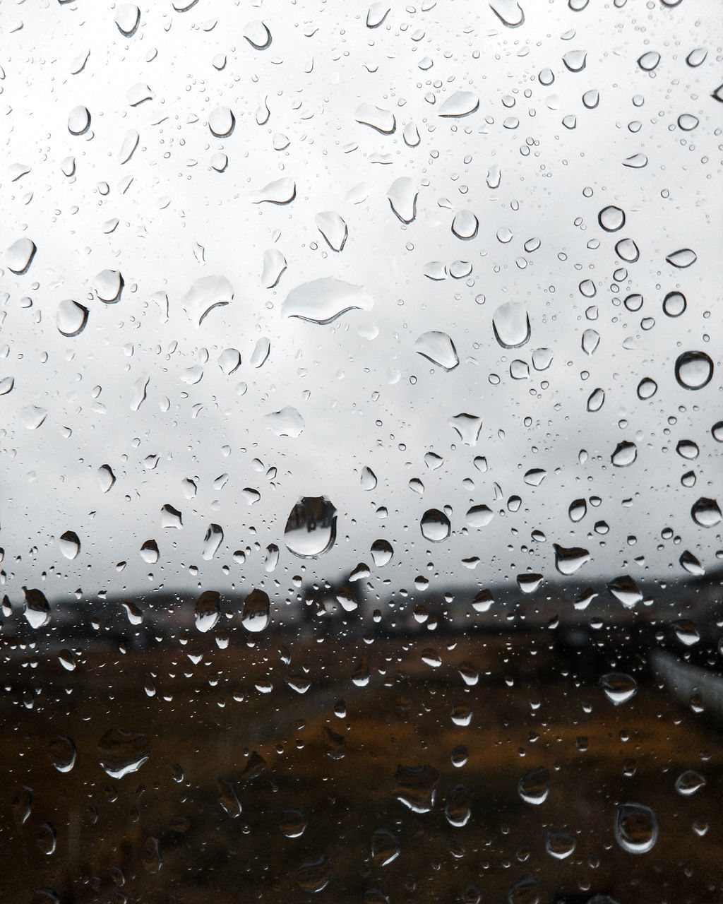 CLOSE-UP OF RAINDROPS ON GLASS WINDOW