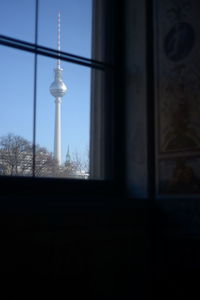 Communications tower against sky seen through glass window