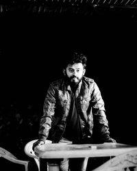 Portrait of bearded man standing by table at night