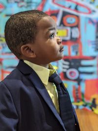 Cute boy looking away while standing indoors