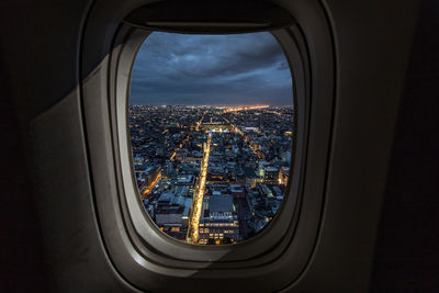 Illuminated cityscape seen through airplane window at night