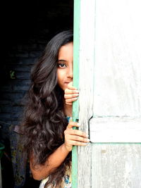 Portrait of beautiful young woman standing against wall