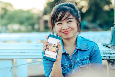 Portrait of smiling young woman using mobile phone outdoors