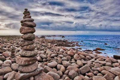 Stack of pebbles on beach against sky