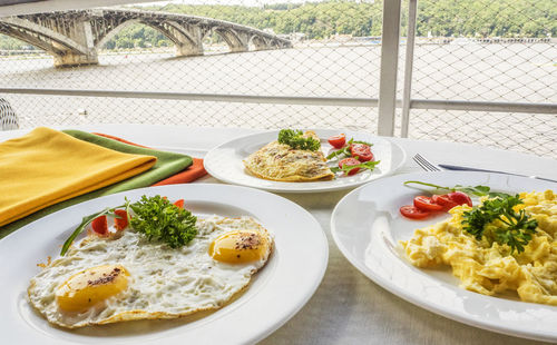 High angle view of omelet with scrambled and fried egg served in plate on table at cafe