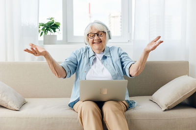 Young woman using laptop while sitting on sofa at home