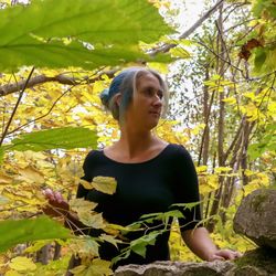 Woman looking away while standing against plants