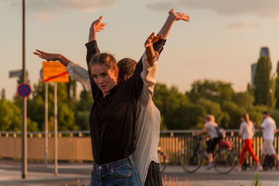 Female friends dancing against sky during sunset