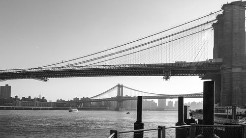 Suspension bridge in city against clear sky