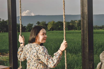 Portrait of woman standing on swing at playground