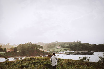 Rear view of woman standing on field against sky