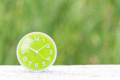 Close-up of green clock on wooden table