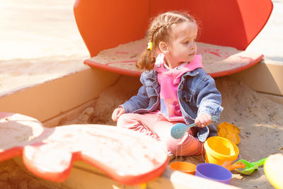 Full length of cute girl playing while sitting on sand