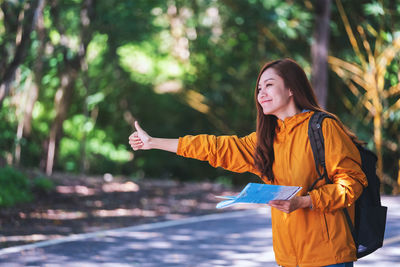 Portrait of young woman standing against trees