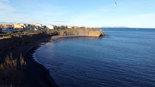 Scenic view of sea by buildings against sky