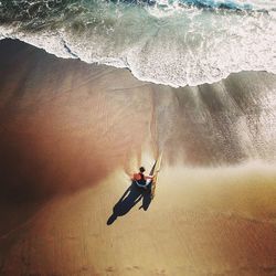 High angle view of man with surfing board on beach