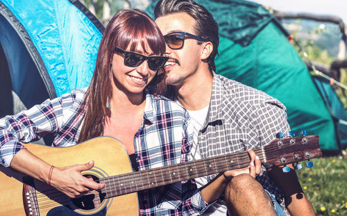 Young couple playing guitar outdoors