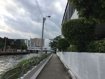 Footpath amidst trees and buildings against sky