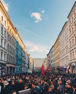 People on street amidst buildings in city against sky