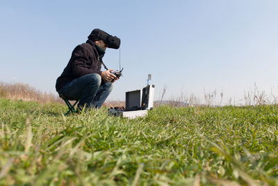 Man using virtual reality simulator while holding drone remote control on grassy field