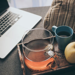 Still life of a natural breakfast at home beside a laptop on the sofa. tea, coffee on a wooden tray 