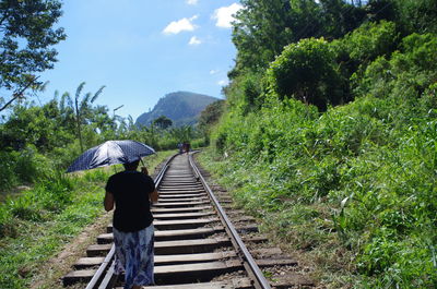 Rear view of man walking on railroad track