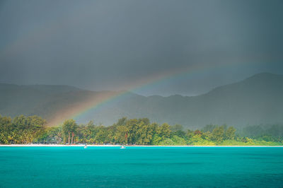 Scenic view of rainbow over sea against sky