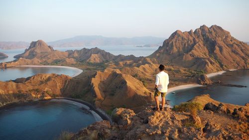 Rear view of man standing on cliff in front of sea