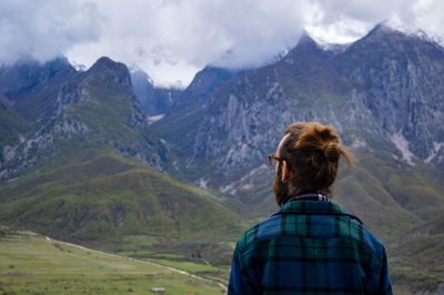 Rear view of man looking at mountains against sky