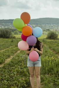 Low section of woman with balloons standing on field