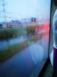 Close-up of wet train window in rainy season
