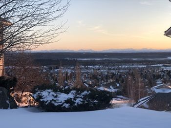 Snow covered landscape against sky during sunset