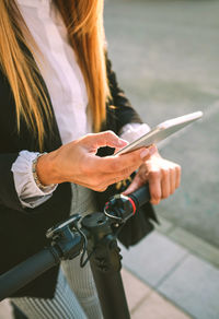 Midsection of woman using phone on footpath