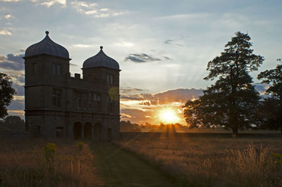 Built structure on field against sky at sunset