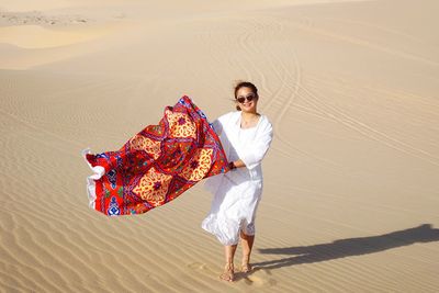 Portrait of smiling young woman on sand in desert