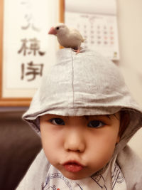 Portrait of cute boy puckering while bird on his head at home