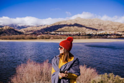 Woman with umbrella standing on mountain against sky