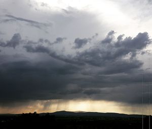 Low angle view of storm clouds over silhouette landscape