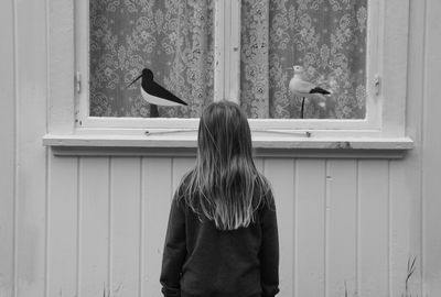 Rear view of woman standing in front of house