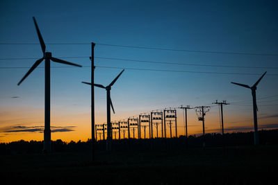 Power generators of windmills at shadow sunset - wind turbine on field at sunset