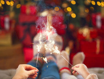 Cropped hands of people holding sparkler at night