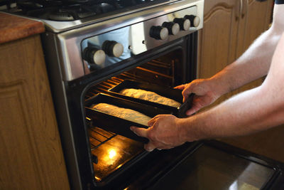 Cropped hands of man preparing food in oven