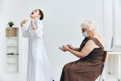 Side view of woman standing against white wall