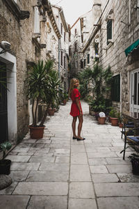 Woman walking on footpath amidst buildings in city