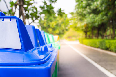 Colorful garbage cans arranged in row on footpath at park